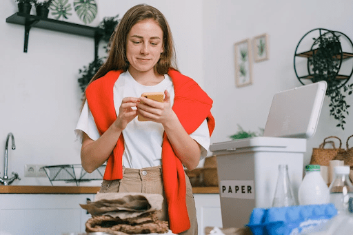 smiling woman sorting waste using phone